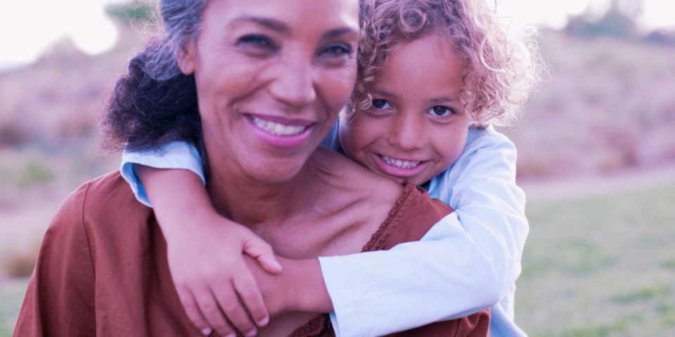 A mother carrying her daughter, smiling.